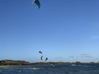 A vibrant kite surfer catching air over turquoise Caribbean waters under a clear blue sky.