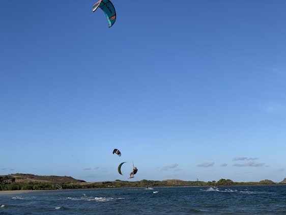 A vibrant kite surfer catching air over turquoise Caribbean waters under a clear blue sky.