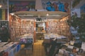 A cozy music store filled with vinyl records and DVDs, featuring colorful graffiti on the walls. Shelves are lined with a vast collection of CDs and records in an organized manner. Soft lighting adds to the inviting atmosphere, and a few customers are browsing the selection.