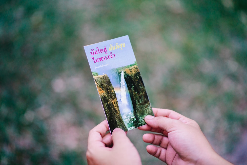 person holding photo of waterfalls