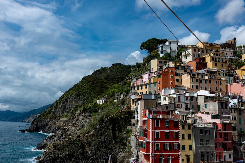 multicolored concrete houses and buildings near mountain viewing blue sea under blue and white skies during daytime