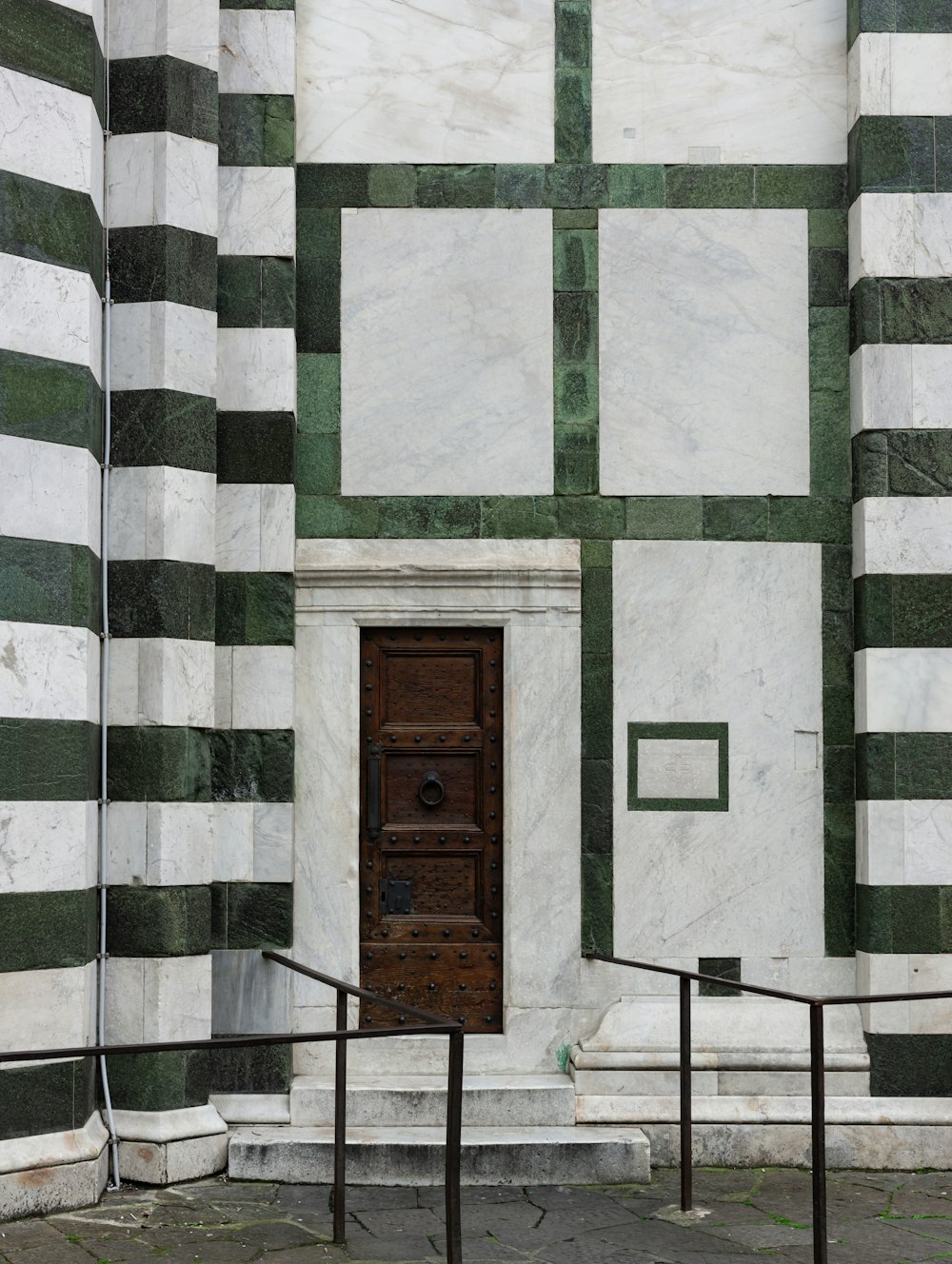 a wooden door in front of a green and white building