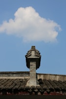 Finished tile roof with a chimney, framed by a clear blue sky.