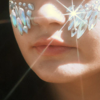 Sparkling party face gem stickers applied around eyes at a festival.