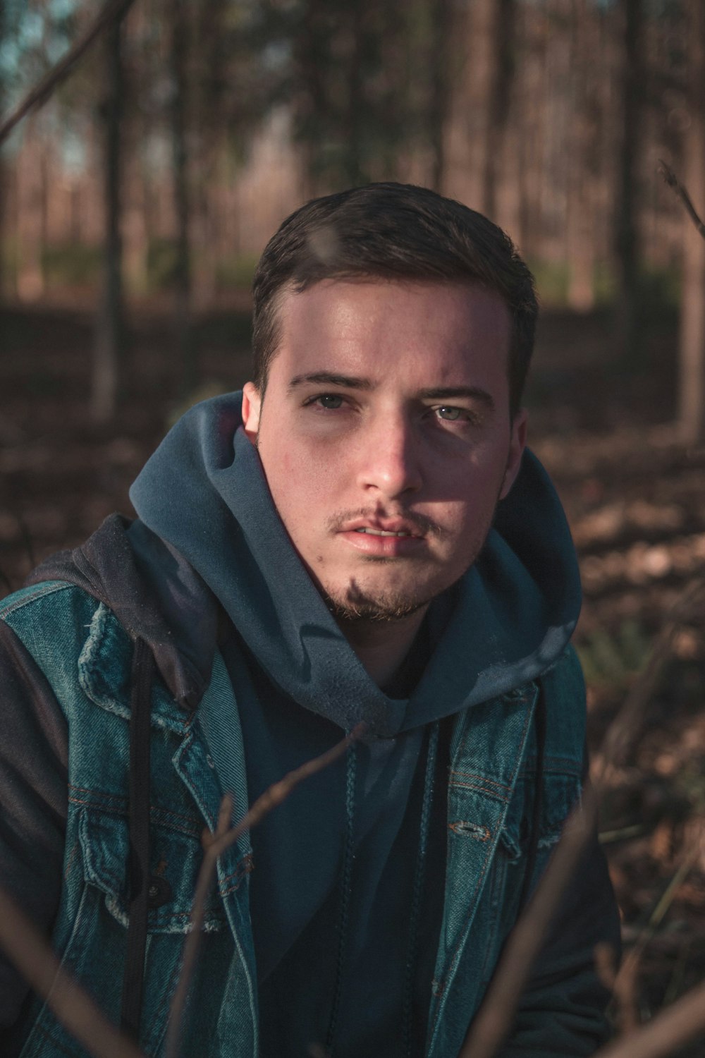 man in blue denim jacket beside trees