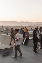 Group of skaters hanging out by a graffiti-covered wall at dusk.