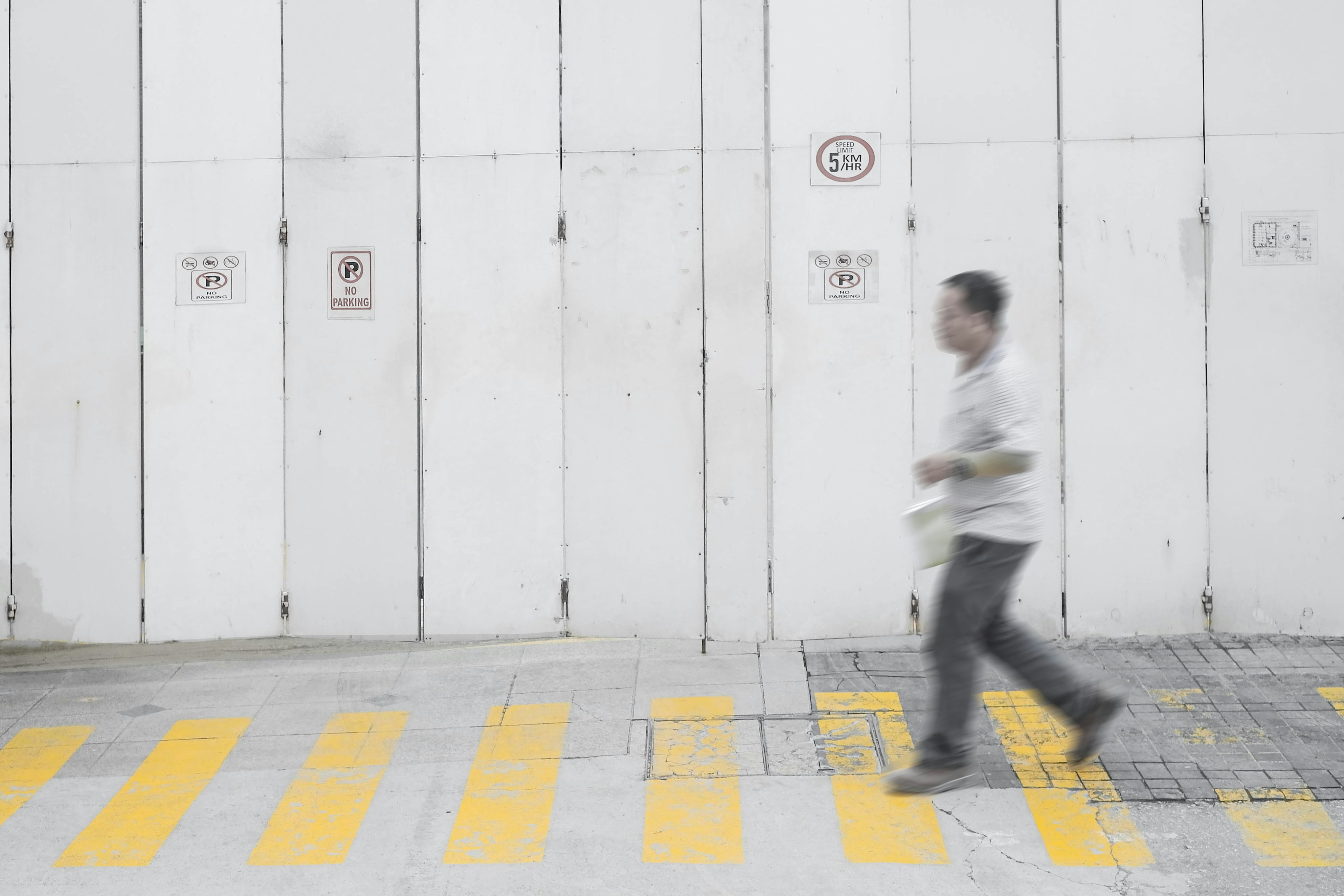 a man walking across a yellow and white cross walk