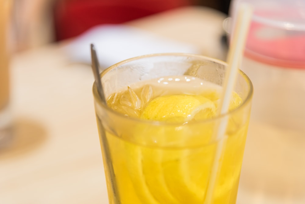 yellow liquid in clear drinking glass with straw