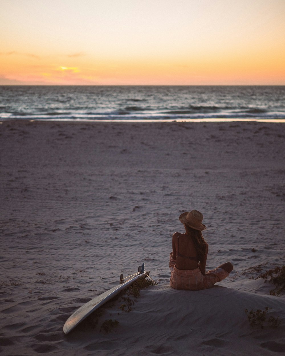 woman sitting and facing near seashore during daytime