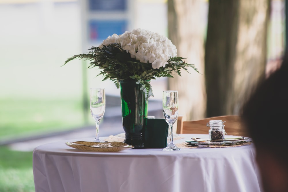 white petaled flowers in green glass vase on table