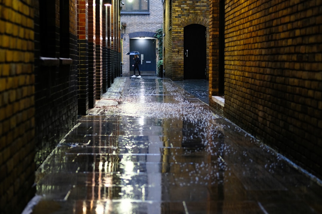 man passing by a narrow street while raining