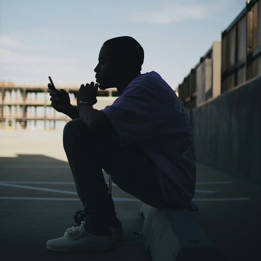 man sitting in the parking lot during daytime