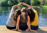 2 women sitting on wooden dock during daytime