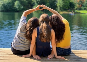 2 women sitting on wooden dock during daytime
