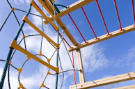 A colorful rope course suspended indoors with children climbing and laughing.