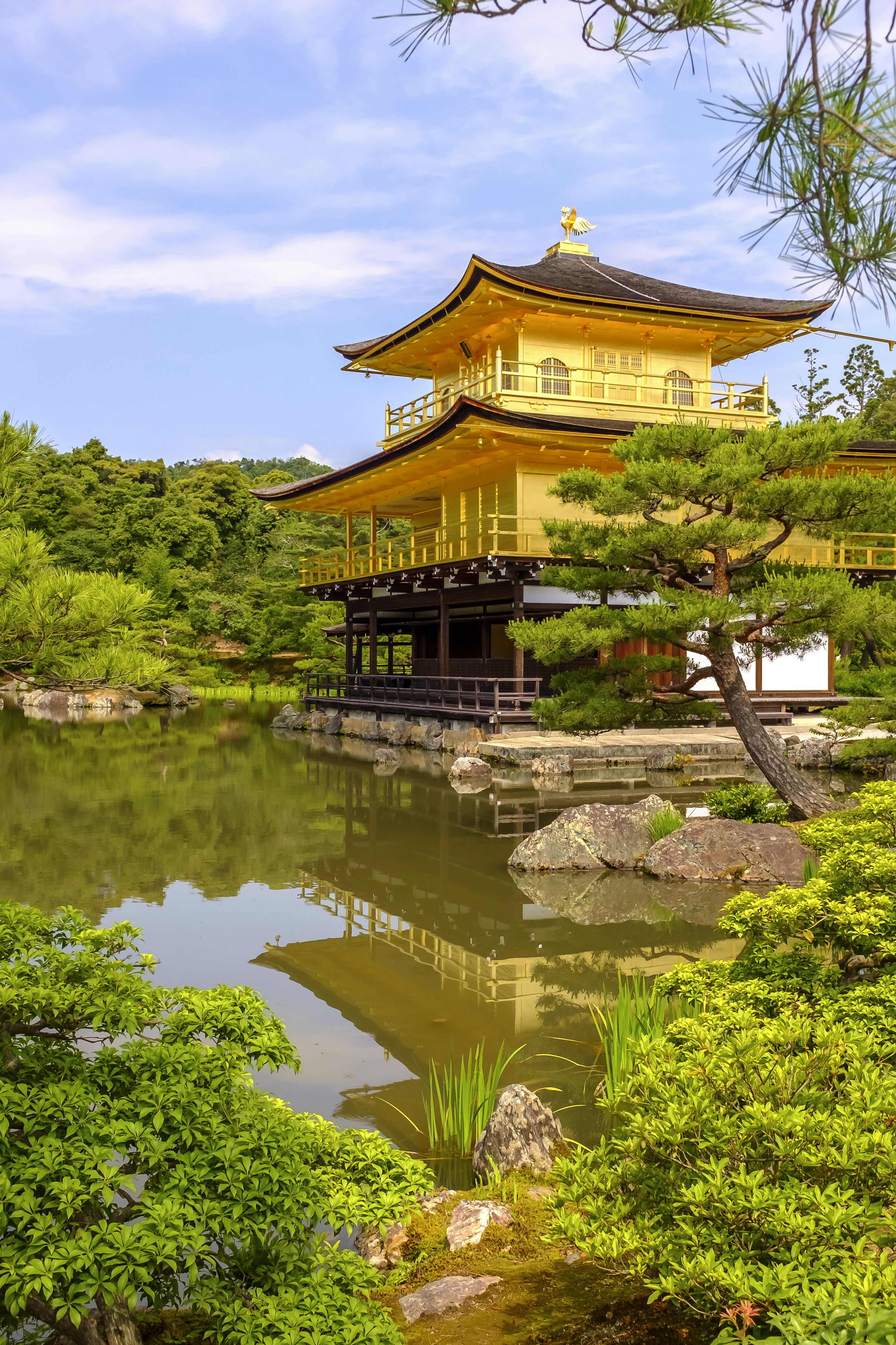 晴朗天空下，京都金閣寺映照在庭園池水之中。