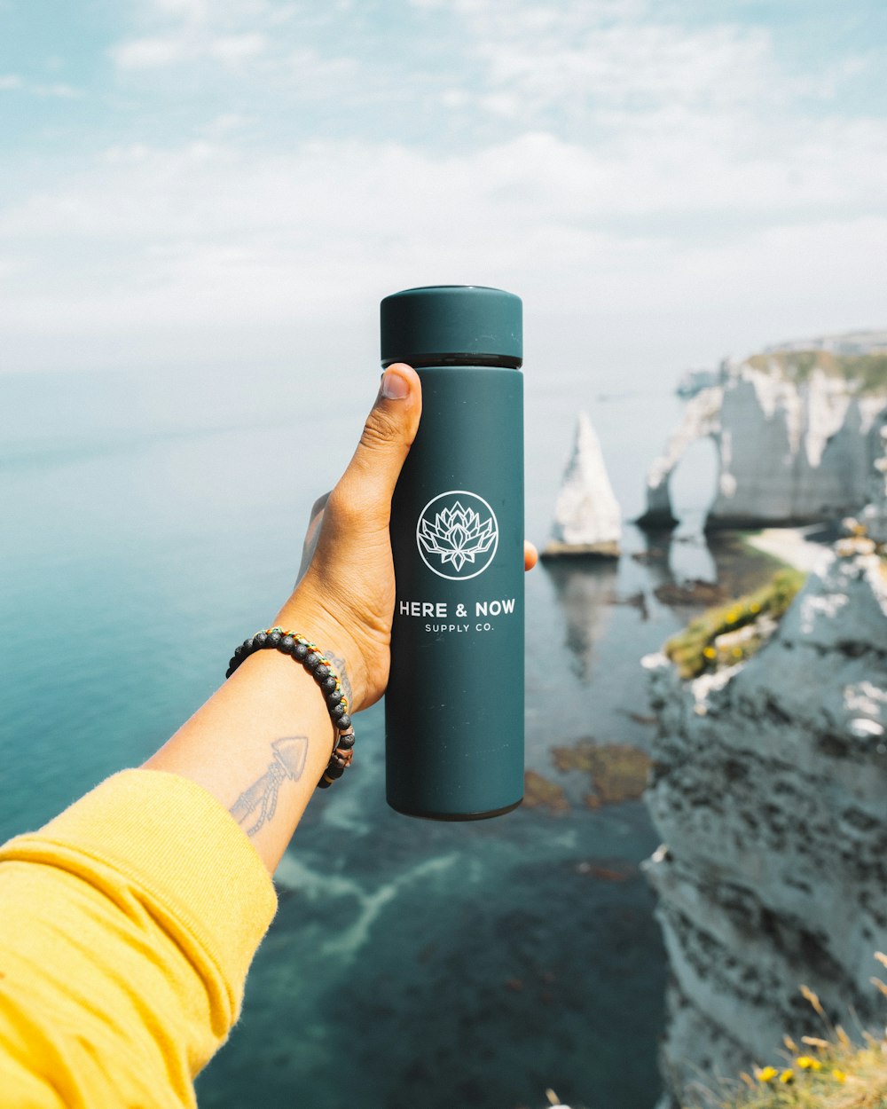 a person holding a water bottle in front of a body of water