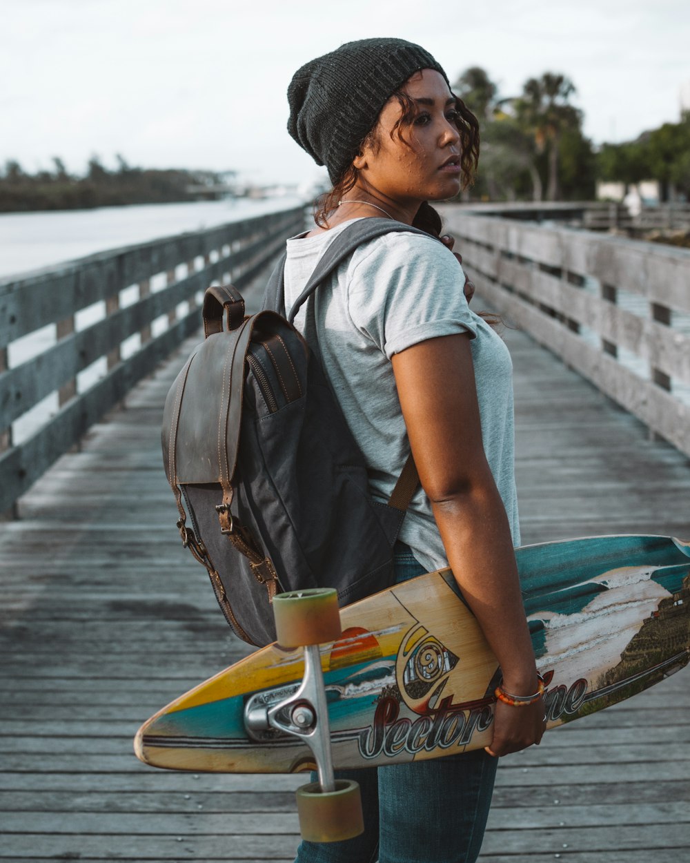 woman holding skateboard while standing on wooden dock