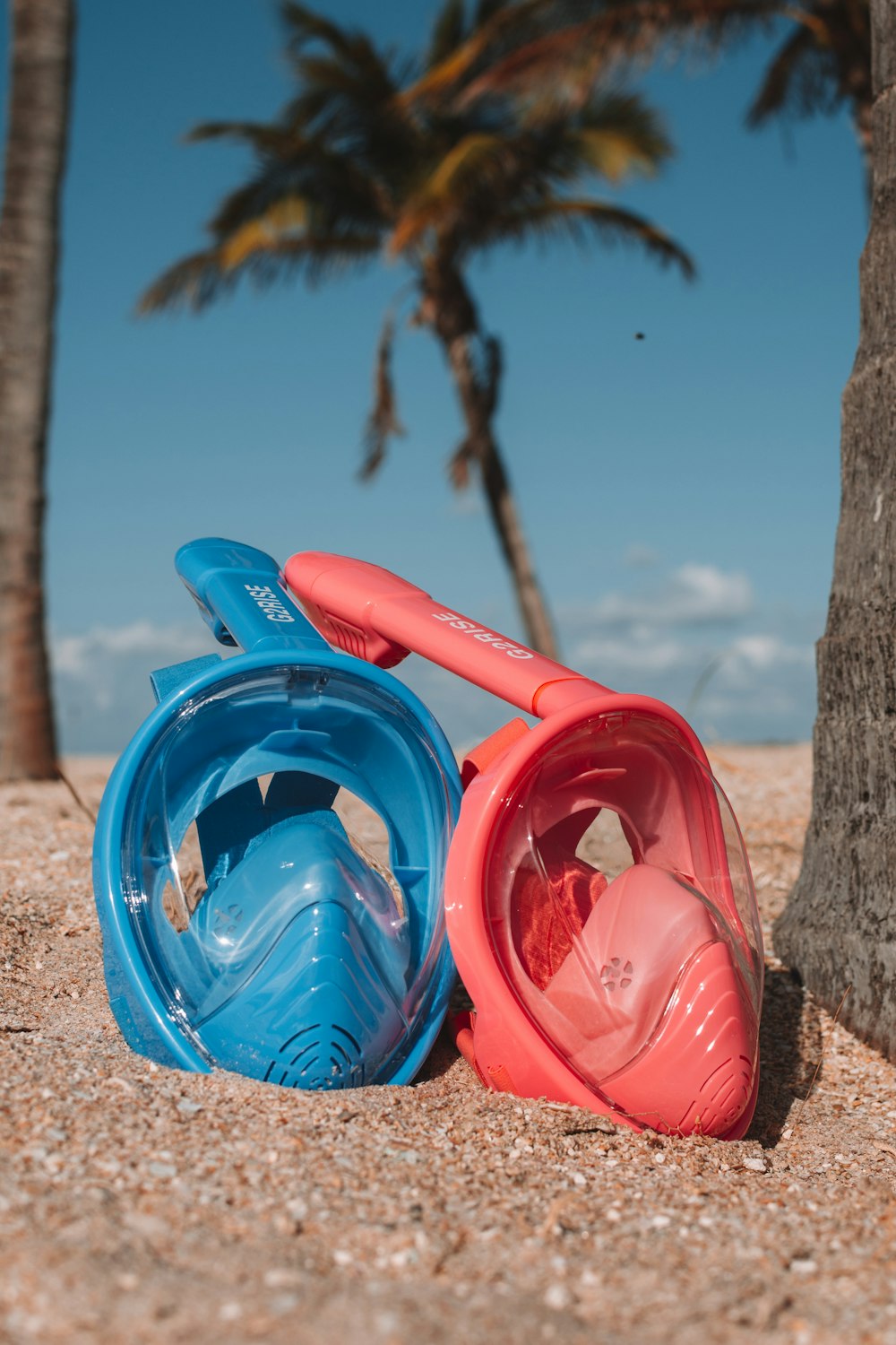 two blue and pink underwater breathing masks on sand