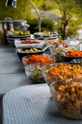 Elegant buffet setup featuring colorful salads and artisan breads at an outdoor wedding.
