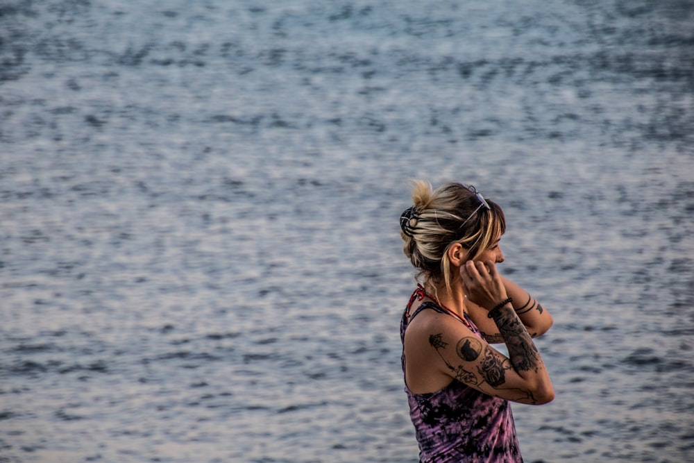 a woman talking on a cell phone next to a body of water