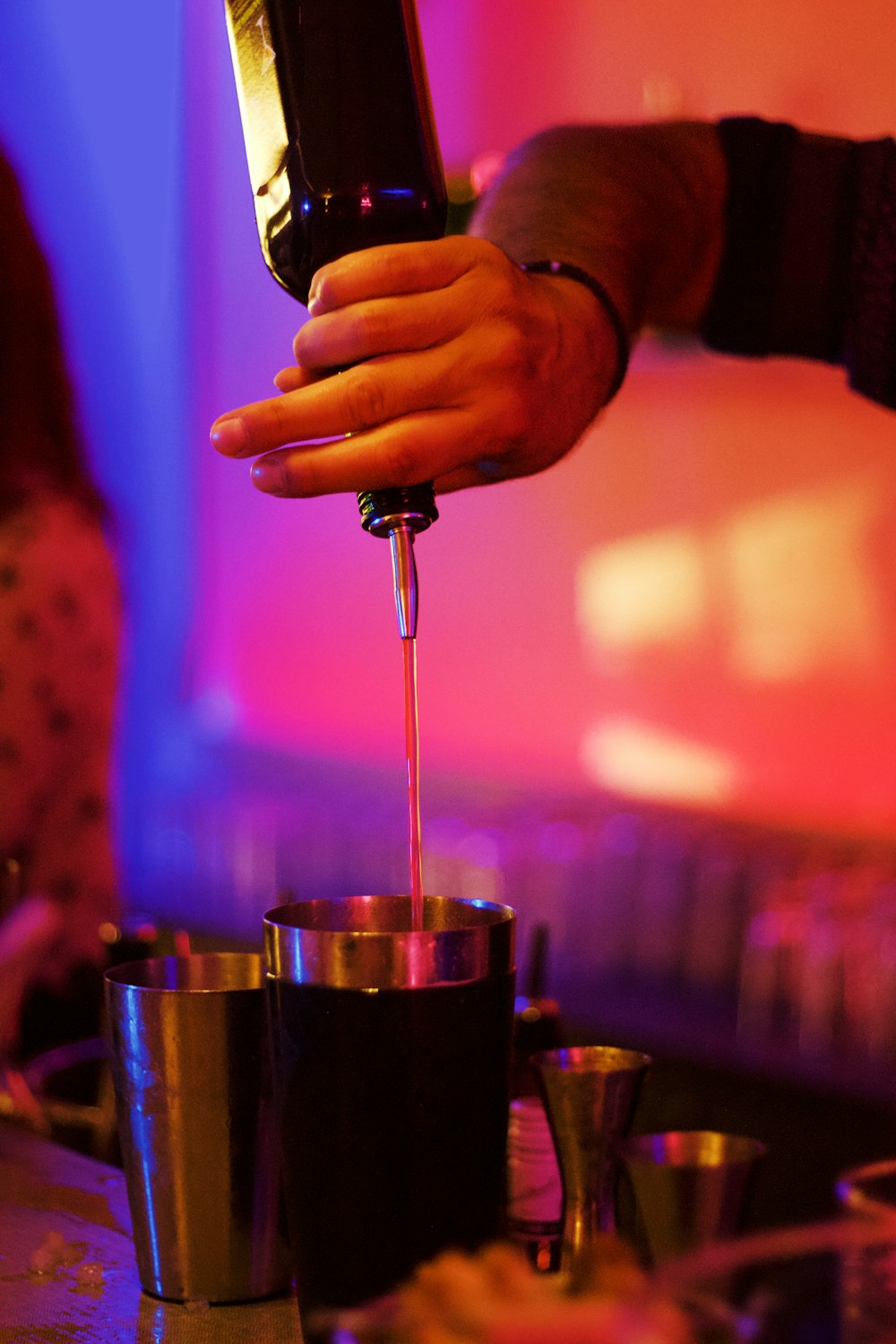 person putting liquid from bottle to cup