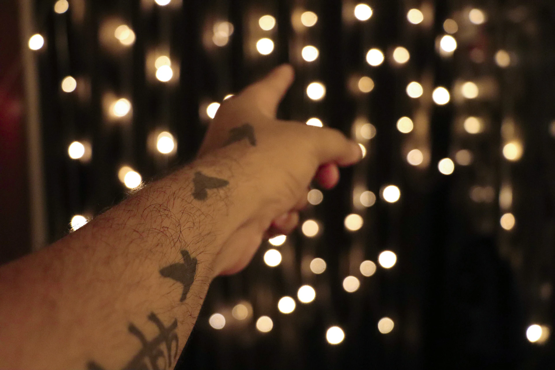 A close-up of a striking black and red geometric tattoo glowing under neon lights with wisps of smoke in the background.