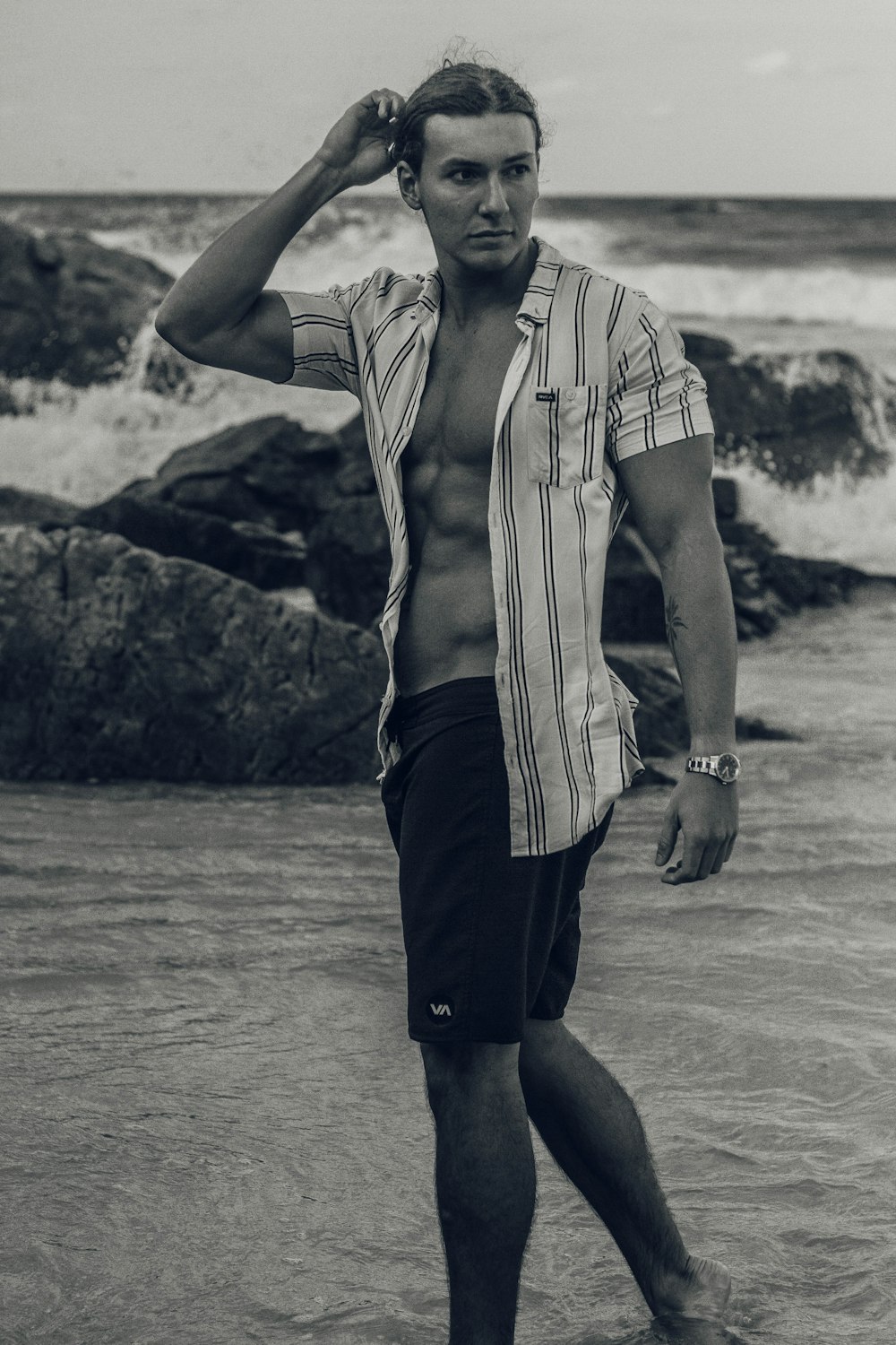 grayscale photo of man standing on seashore