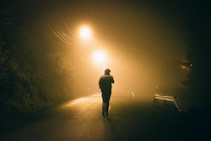 man standing in concrete road during night time