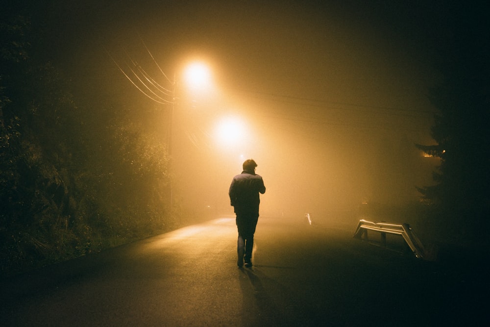 man standing in concrete road during night time