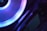 A close-up view of a computer component with a glowing LED ring in shades of blue and purple. The logo 'ASRock' is visible on the device, highlighting part of the internal hardware setup.