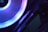 A close-up view of a computer component with a glowing LED ring in shades of blue and purple. The logo 'ASRock' is visible on the device, highlighting part of the internal hardware setup.
