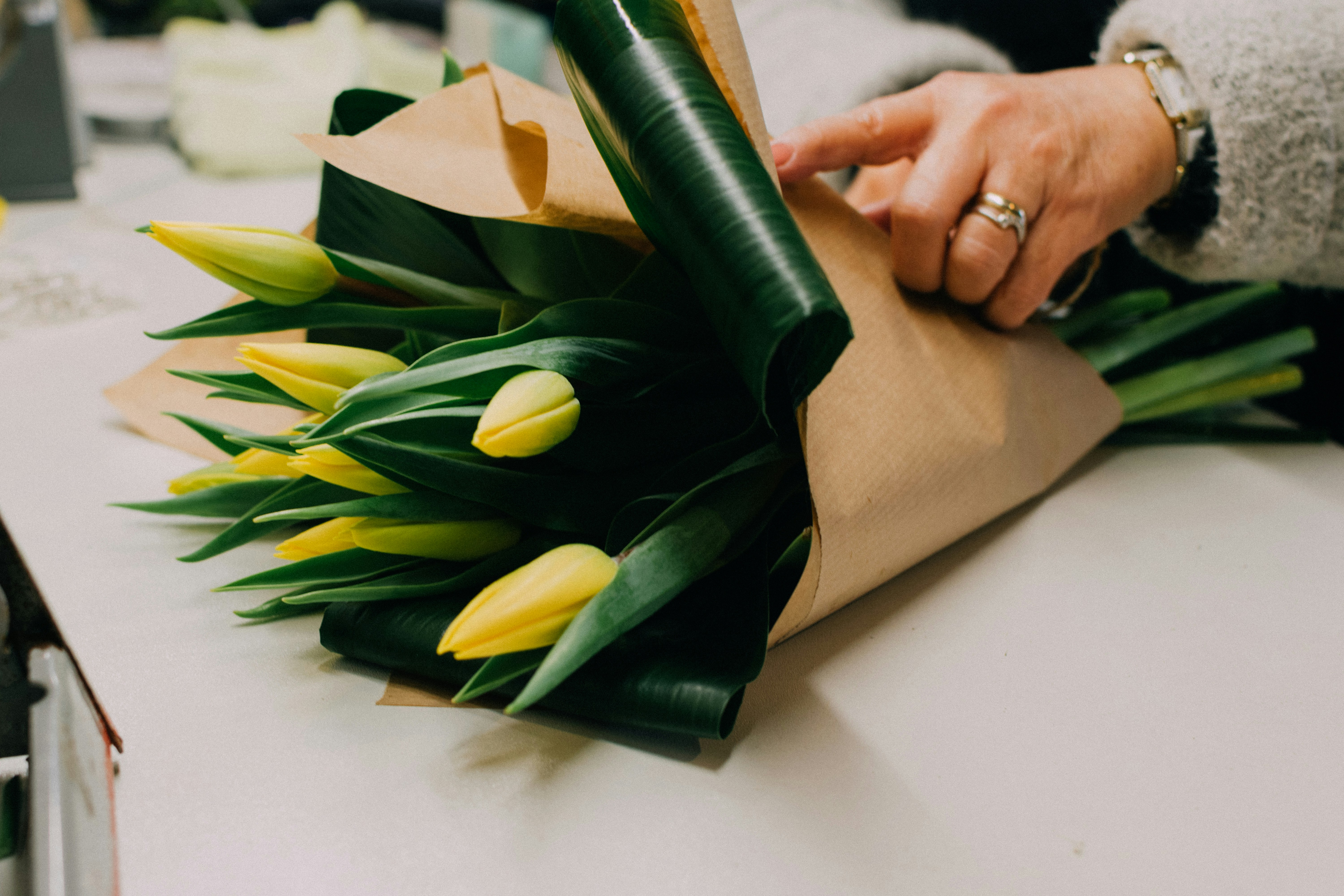 Florist wrapping a fresh flower bouquet by hand at Canna Lilies for Africa