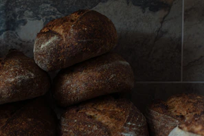 Stack of golden, crusty breads with a soft, airy interior, photographed with natural light.