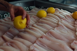 Fresh fish fillets elegantly arranged with lemon slices and greens.