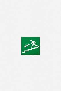 A green emergency exit sign featuring a white pictogram of a person descending stairs with an arrow pointing downwards and to the left.