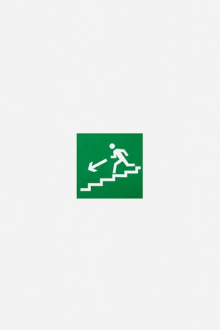A green emergency exit sign featuring a white pictogram of a person descending stairs with an arrow pointing downwards and to the left.