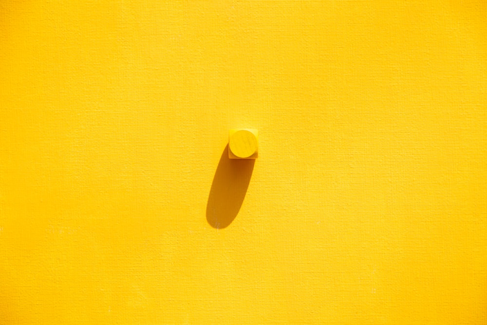 a close up of a yellow wall with a button