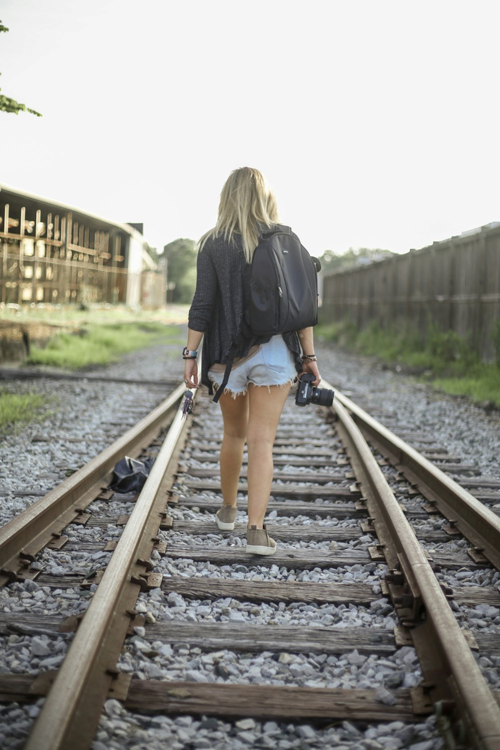 woman walking on train rails during daytime