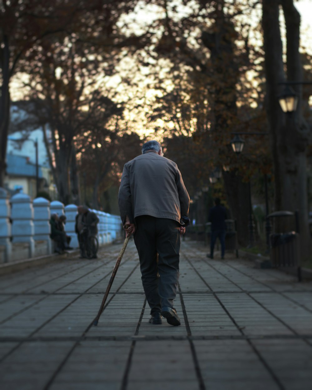 man walking on street holding cane