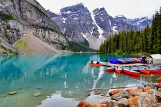 A crystal-clear mountain lake in Romania reflecting pine-covered peaks with a single canoe gliding across.