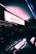 A glowing neon sign for a drugstore with the name 'ARAUJO' is prominently displayed. The sign casts a colorful reflection on the surface of a parked car nearby, creating a vibrant and moody atmosphere. The surroundings are dimly lit, suggesting a night-time or twilight setting.