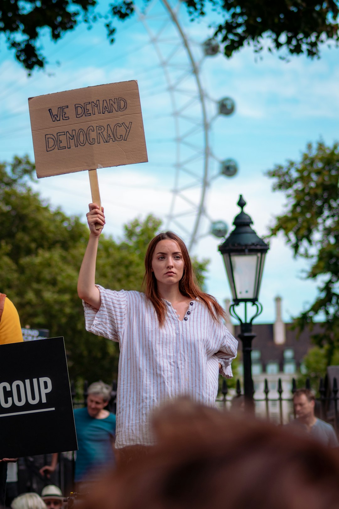 A woman holding a sign saying "We demand democracy".