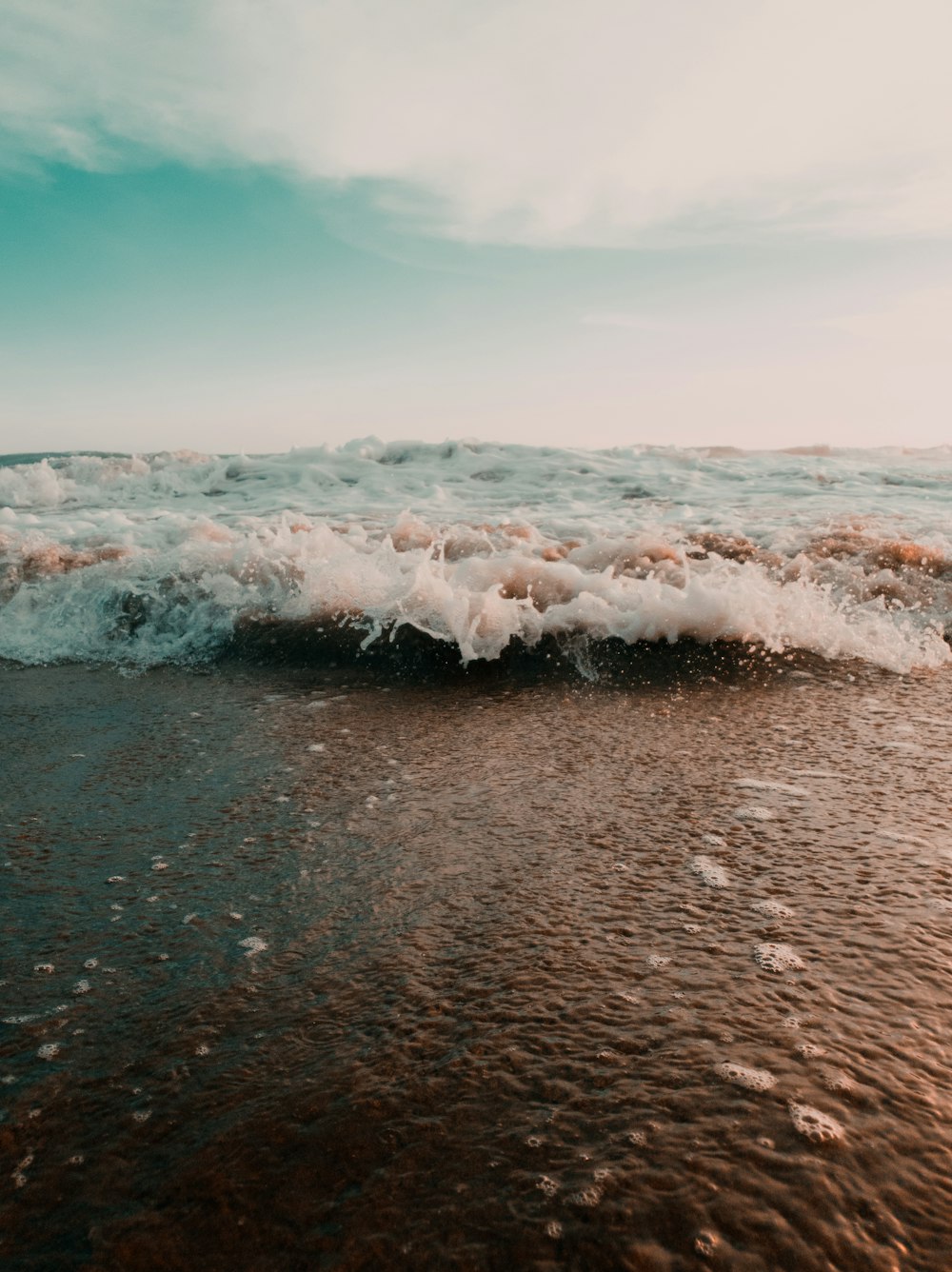 a wave crashing into the shore of a beach