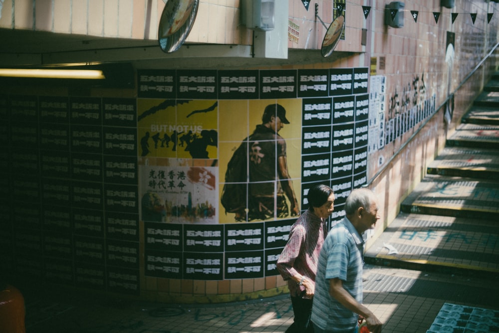personnes marchant près d’un mur avec des affiches