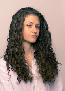 Elegant styled curly hair with soft highlights, showcasing volume and shine.