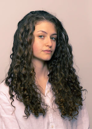 Side profile of a person with voluminous, healthy curly hair glowing in natural light.