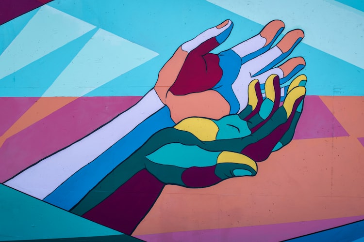A mural on an outside wall with stylized painting of hands, outstreched facing upwards and cupped, as if ready to receive help.