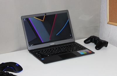 A high-performance laptop open on a desk with gaming accessories around it
