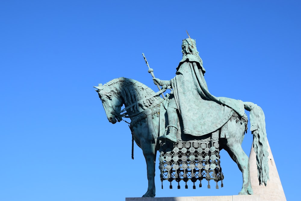 low-angle photography of man riding horse statue under calm blue sky